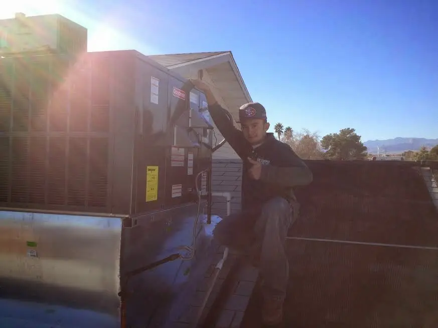 HVAC technician performing AC Tune-Up on a rooftop unit in Potsdam